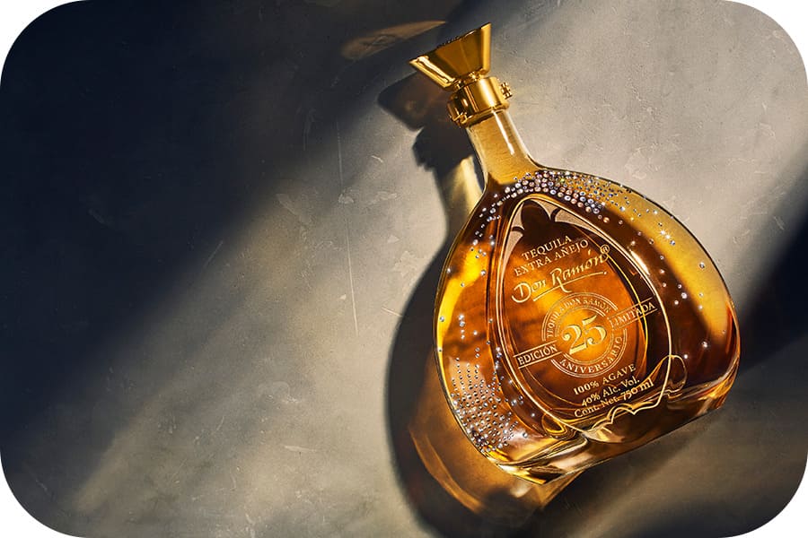 Botella de Tequila Don Ramón de lujo recostado sobre una supercicie que es iluminada por la luz del sol.